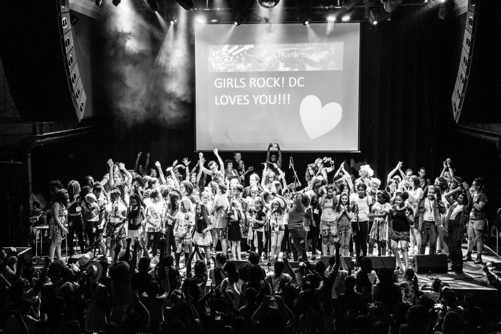 Particpants onstage in front of a poster that says they love the crowd