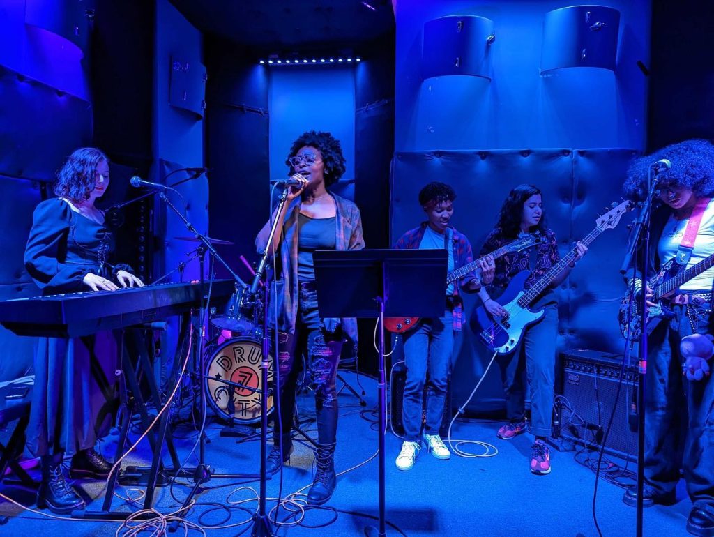 A band performing onstage under blue light