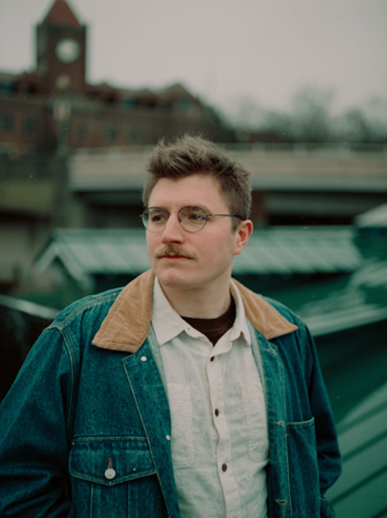 Eli Walfz - Eli Waltz profile, looking into distance leaning against wall
