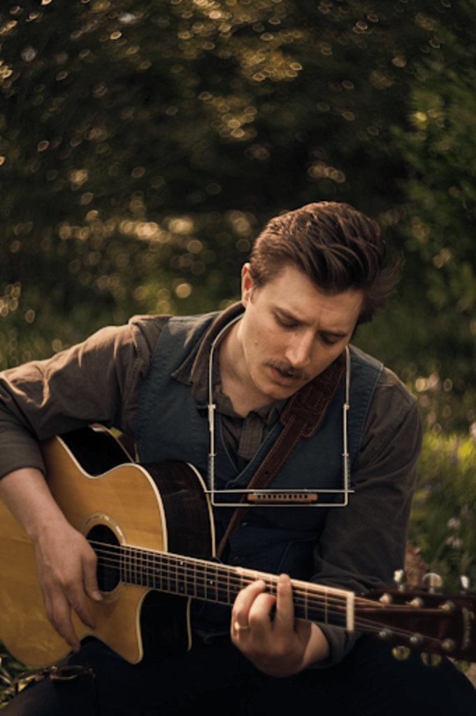 Eli Walz plays an acoustic guitar.