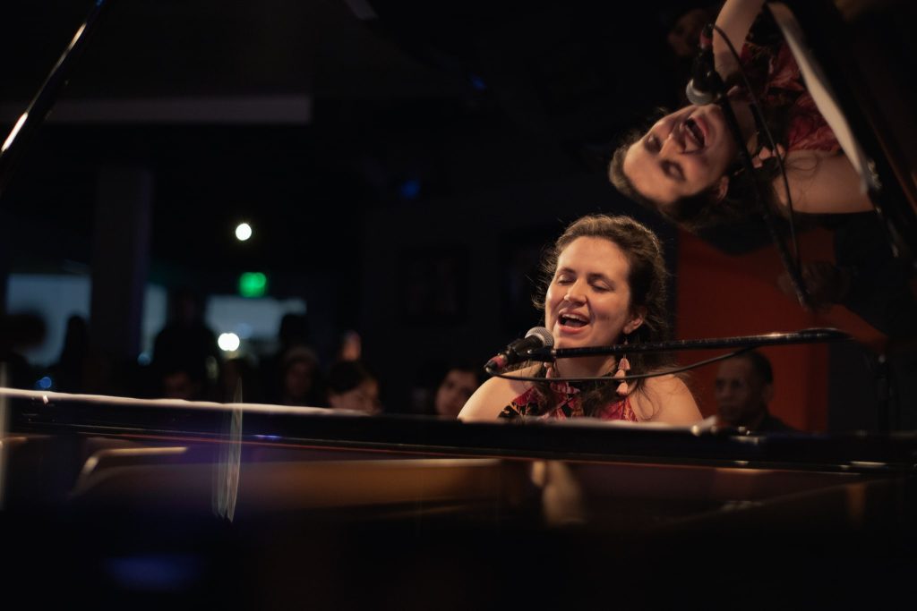 Amy performing at a piano that reflects her