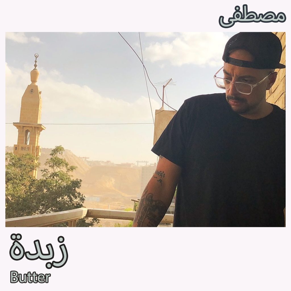 Album art for "Butter" featuring Mostafa wearing a black shirt, glasses, and a black, backwards baseball cap while standing on a deck in Cairo with buildings, trees, and mountains in the background.