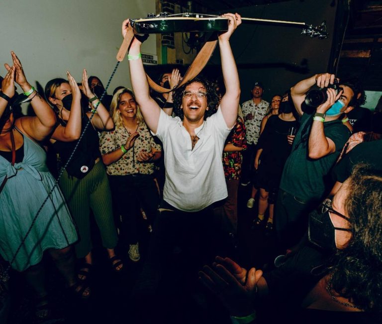Zack holding guitar above his head in a crowd