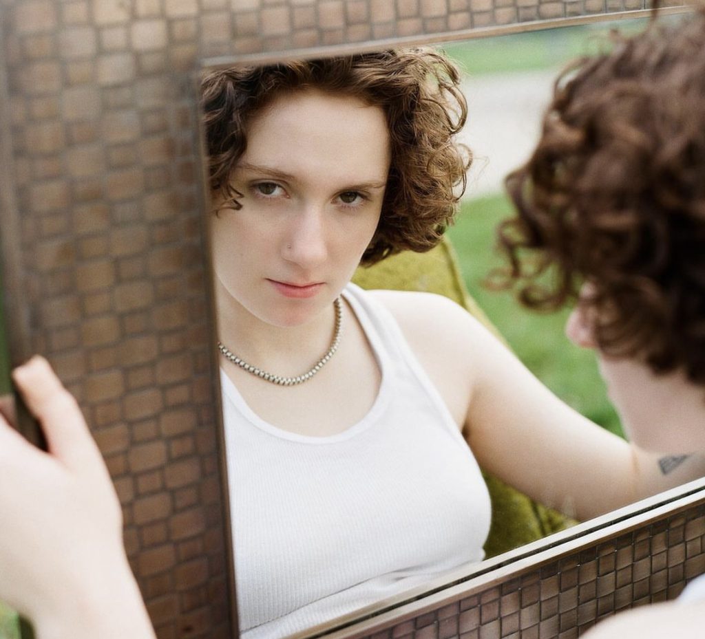 Zola Simone looking at herself in a mirror