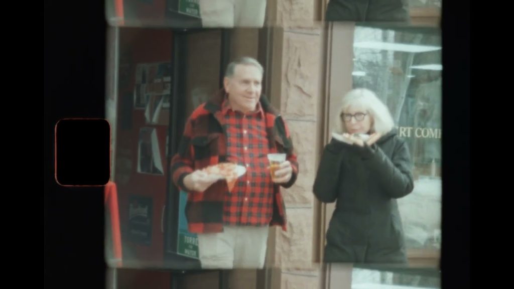 An elderly man and woman stand beside one another.