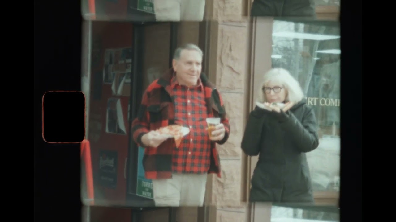 An elderly man and woman stand beside one another.