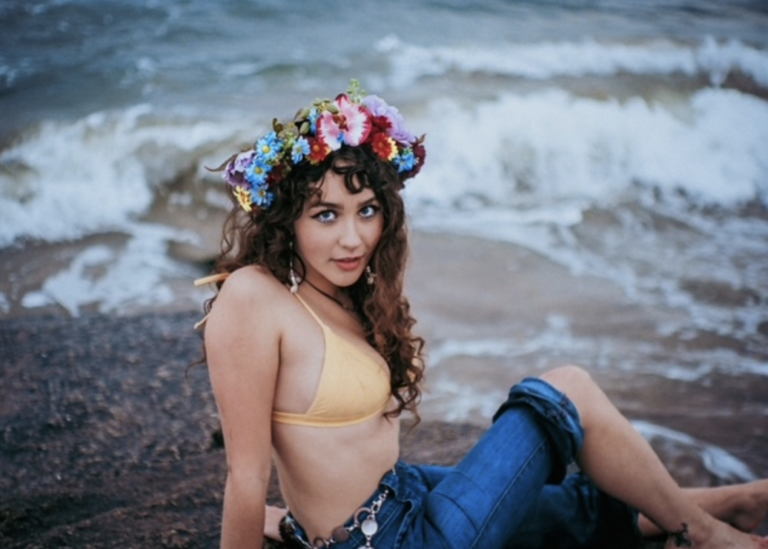 Calista Garcia sits on a beach as the waves gently crash onto the shore.