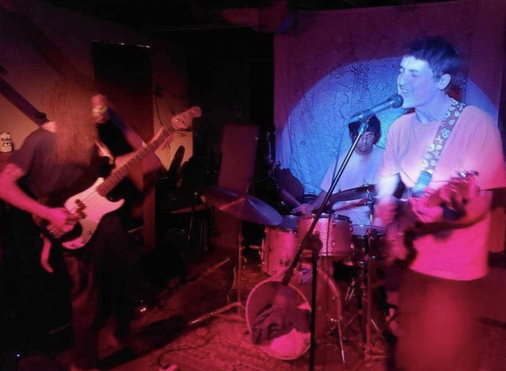 Poppy Patica performing at album release show with Hartmann in the spotlight playing guitar