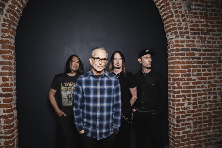 Members of Everclear standing underneath a brick archway.