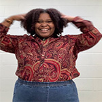 Contributing writer Kaiana Lee smiles for the camera wearing a paisley shirt and blue jeans.