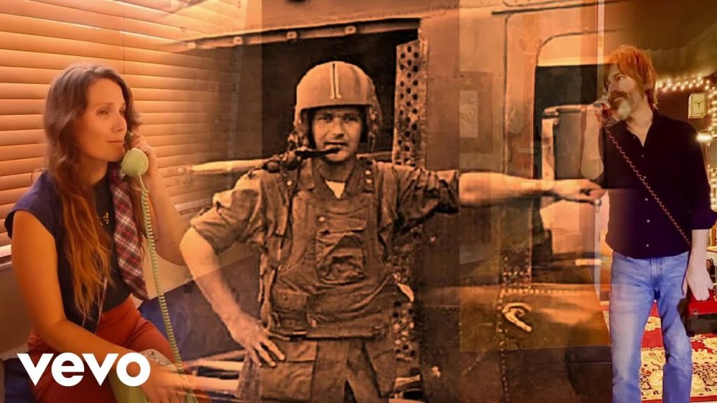 Screenshot from the music video for "Long Distance 1970" depicting a woman and man on the phone with a grainy photo of a man dressed in military uniform in between.