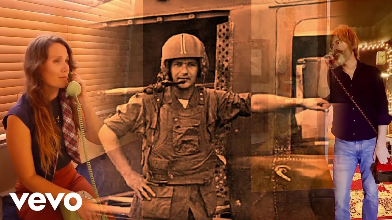 Screenshot from the music video for "Long Distance 1970" depicting a woman and man on the phone with a grainy photo of a man dressed in military uniform in between.