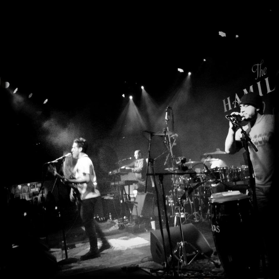 black and white photo of two men performing in front of a sign that says "The Hamilton"
