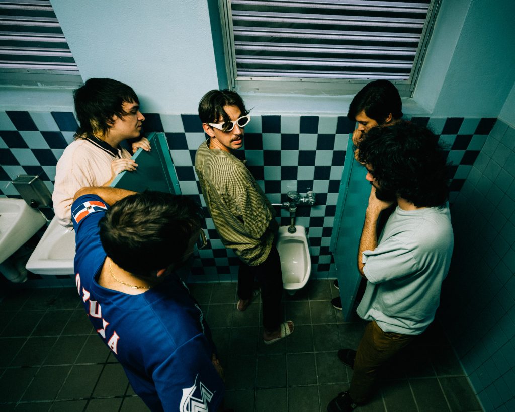 Mustard Service pose around a urinal in a vintage bathroom for a press photo shoot.