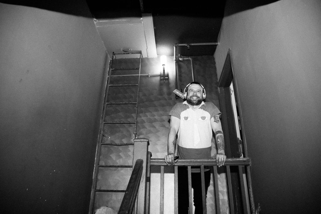 A black and white photo of Say Anything vocalist Max Bemis standing at the top of a staircase.