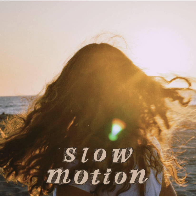 Maggie Cubillos on a beach facing away from the camera and looking into the sky, with 'Slow Motion' written in peach text on the bottom of the image.