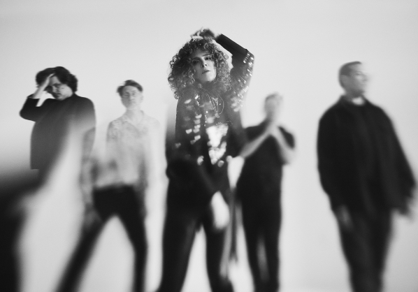 A black and white image of Vakili Band, standing behind a light flare.