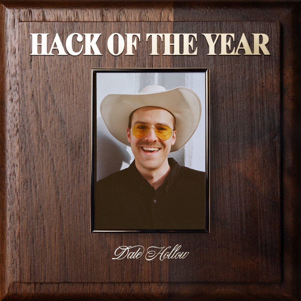On a plate that imitates an Employee of the Year award, a portrait of Dale Hollow is hung with Hack of The Year written above his portrait in gold lettering, while his name is below it.