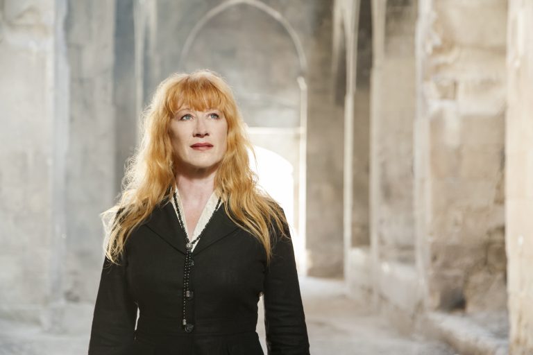 Loreena McKennitt stands in front of a stone archway