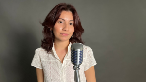 Indie Maryland-based artist Mia Celeste poses in front of microphone smiling slightly.