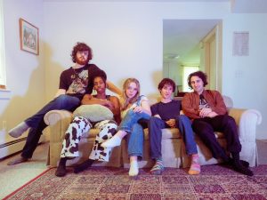 The members of Night Hawk are sitting on a tan couch, facing the camera.