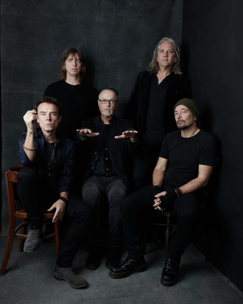 The members of The Church are dressed in varying shades of gray against a gray backdrop