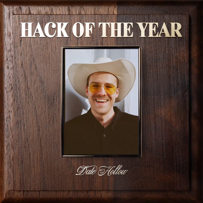 On a plate that imitates an Employee of the Year award, a portrait of Dale Hollow is hung with Hack of The Year written above his portrait in gold lettering, while his name is below it.